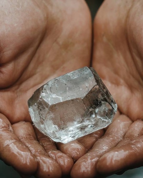 Pair of hands holding a rough natural diamond