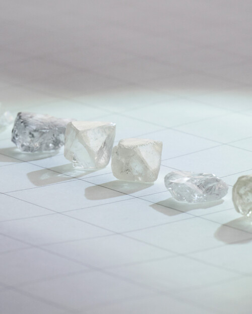 six natural diamonds lined up on a quadricular paper sheet